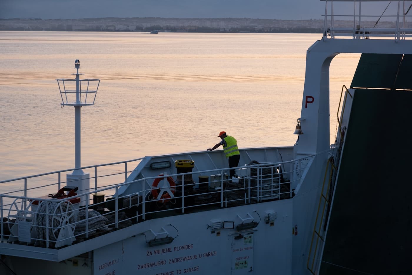 Crew member working on a vessel deck at sunset