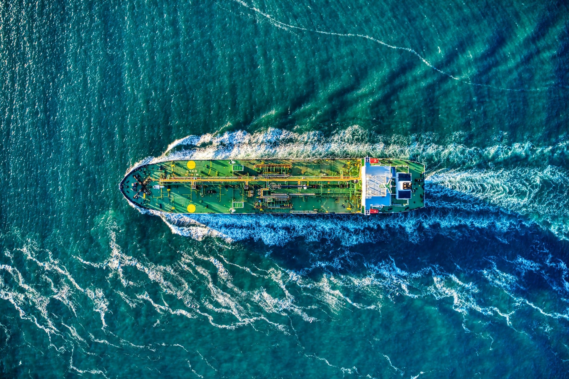 Aerial view of a tanker under way at sea, cutting a wake across open water